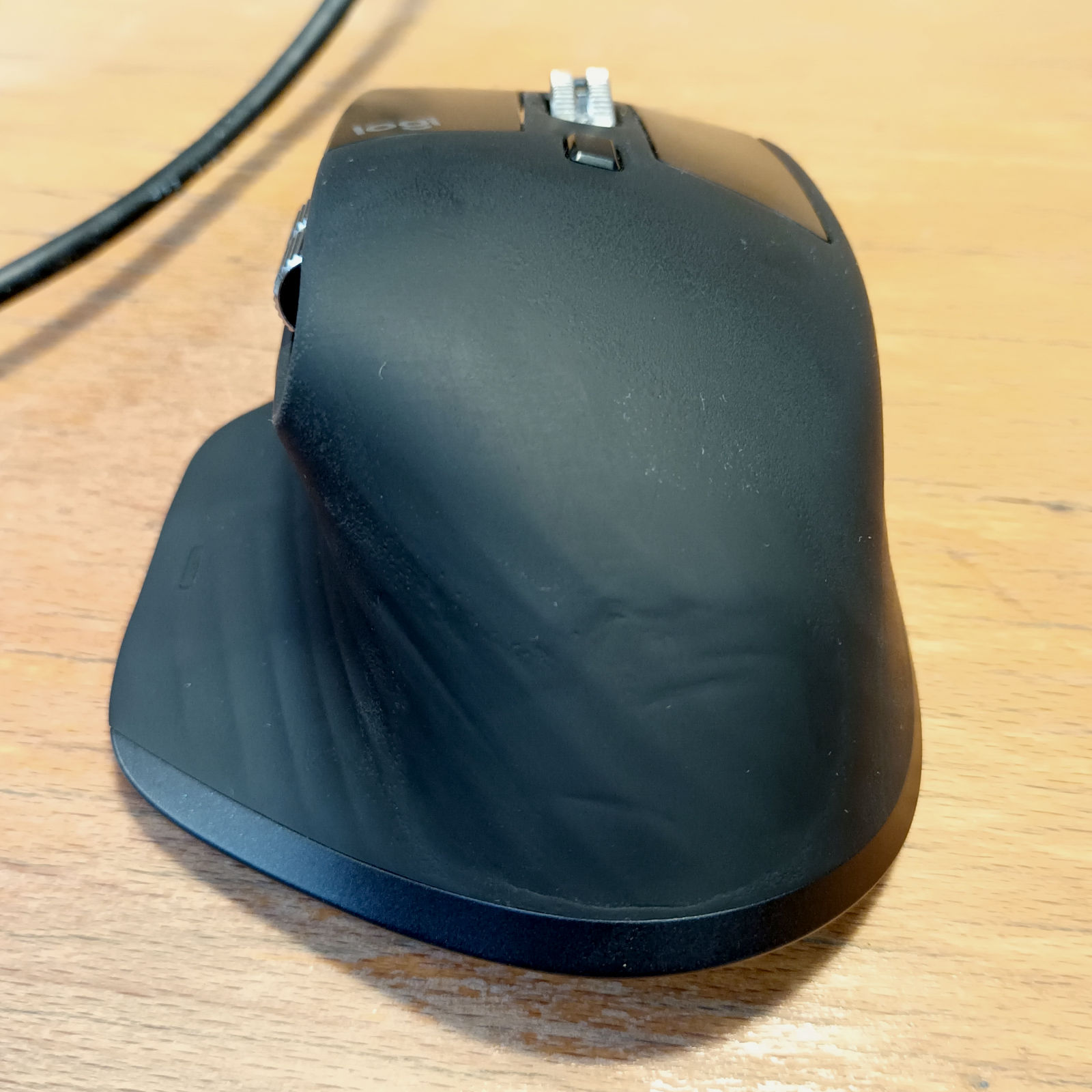 Logitech MX Master 3 mouse (black) with scratches but no peeling rubber on the back. The area where the back contacts with the palm was abraded away.